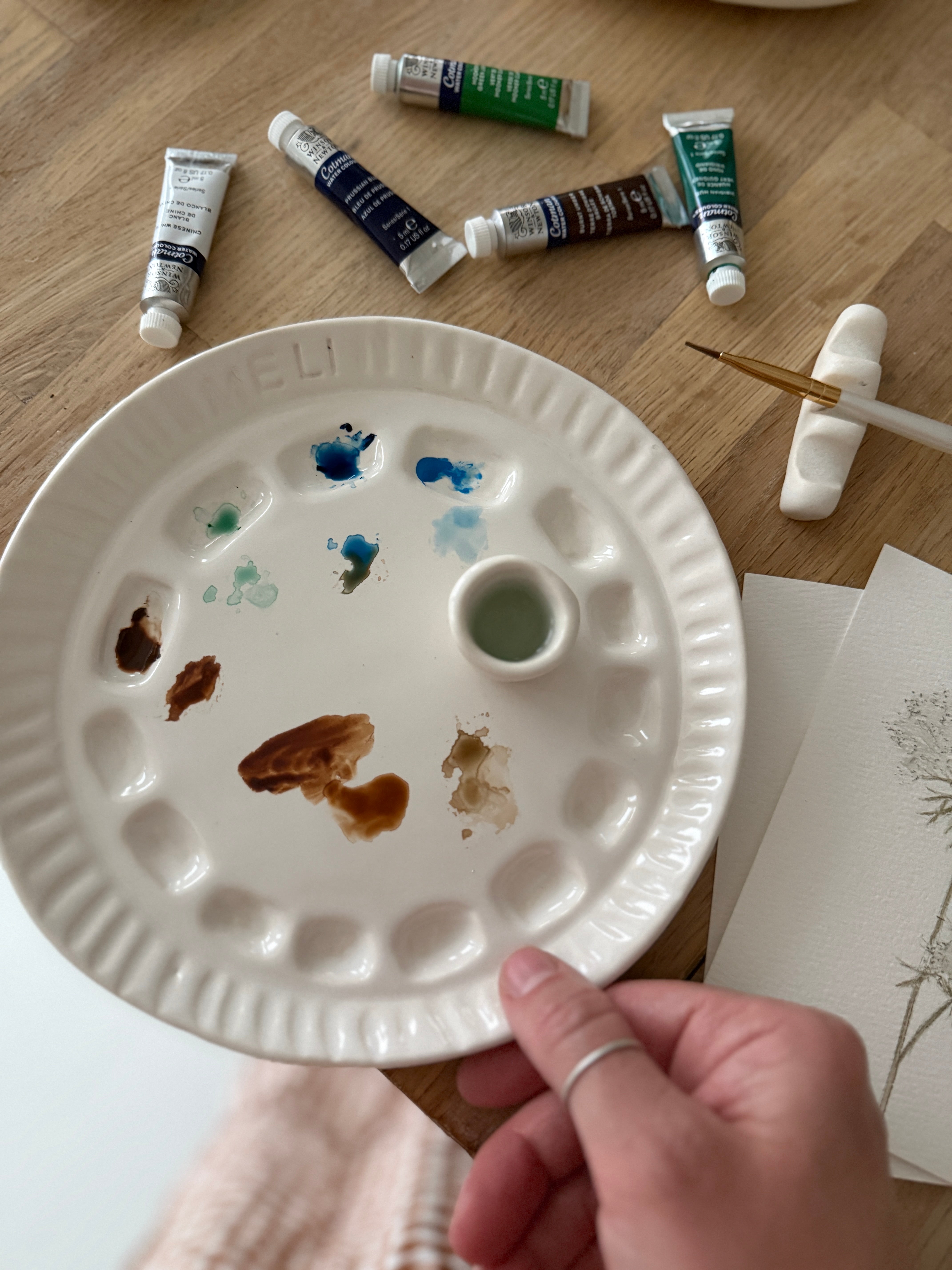 Handmade ceramic watercolor paint palette with mixing wells, a small water cup, and a brush holder.