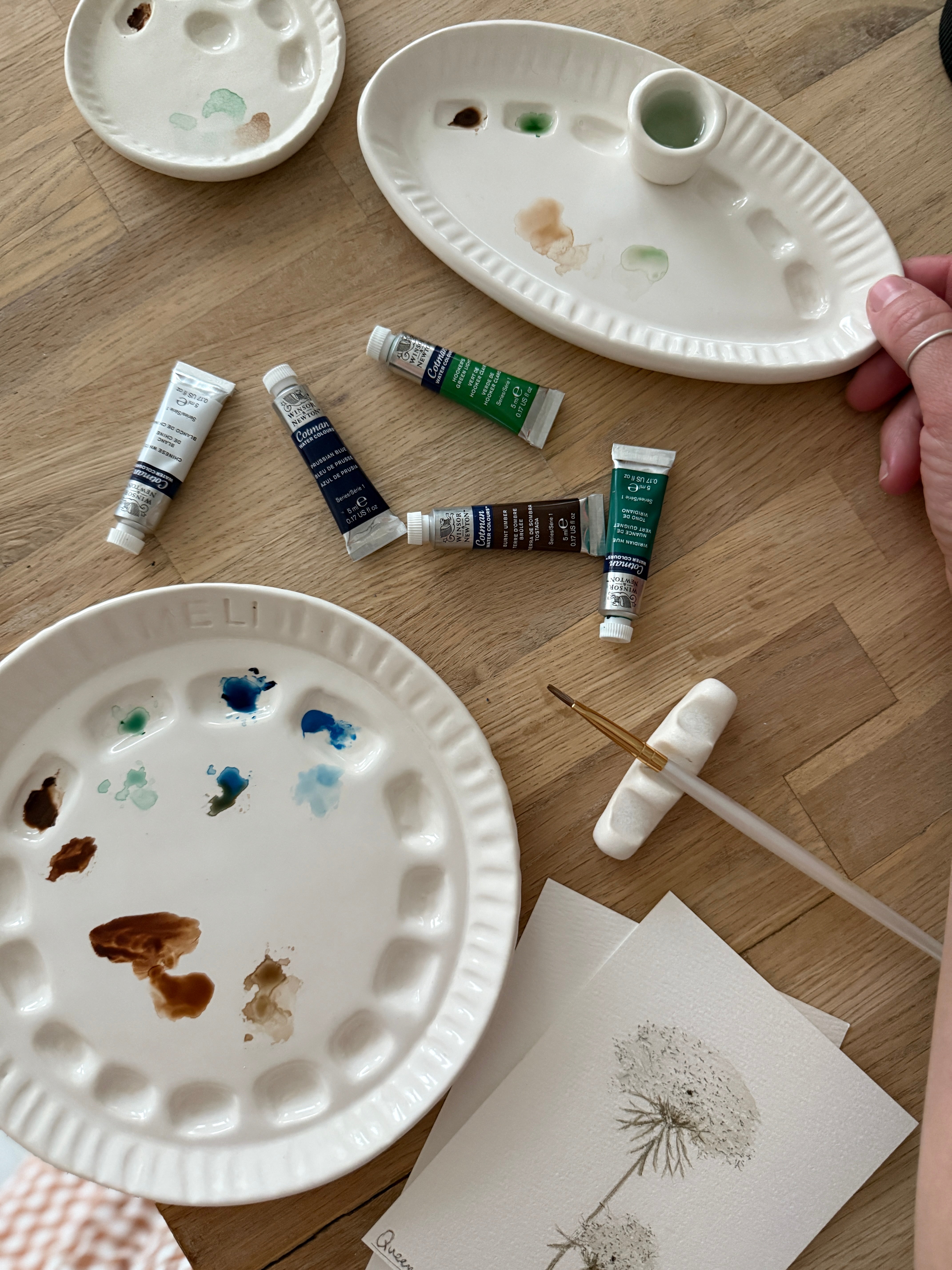 Handmade ceramic watercolor paint palette with mixing wells, a small water cup, and a brush holder.