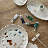 Handmade ceramic watercolor paint palette with mixing wells, a small water cup, and a brush holder.