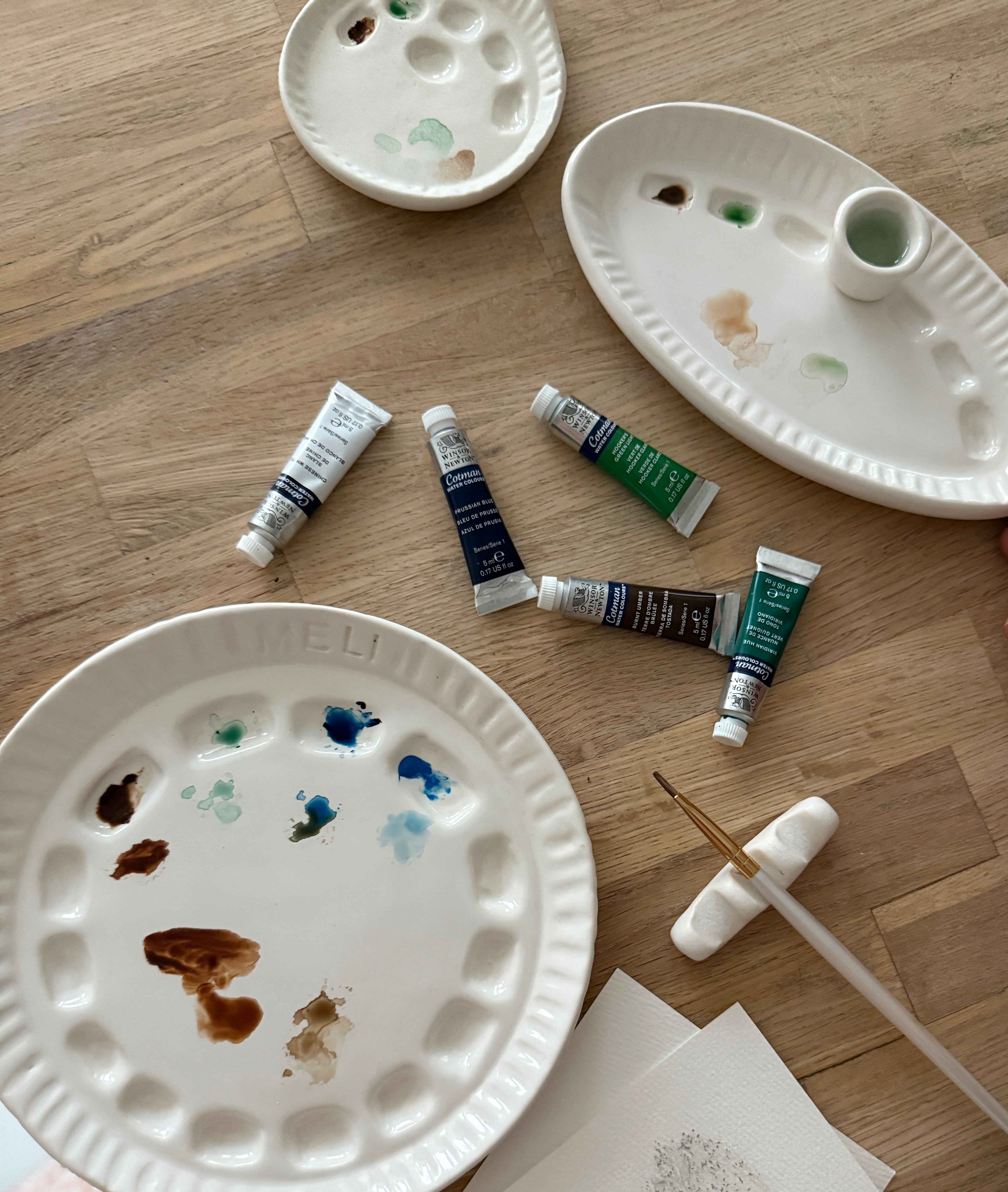 Handmade ceramic watercolor paint palette with mixing wells, a small water cup, and a brush holder.