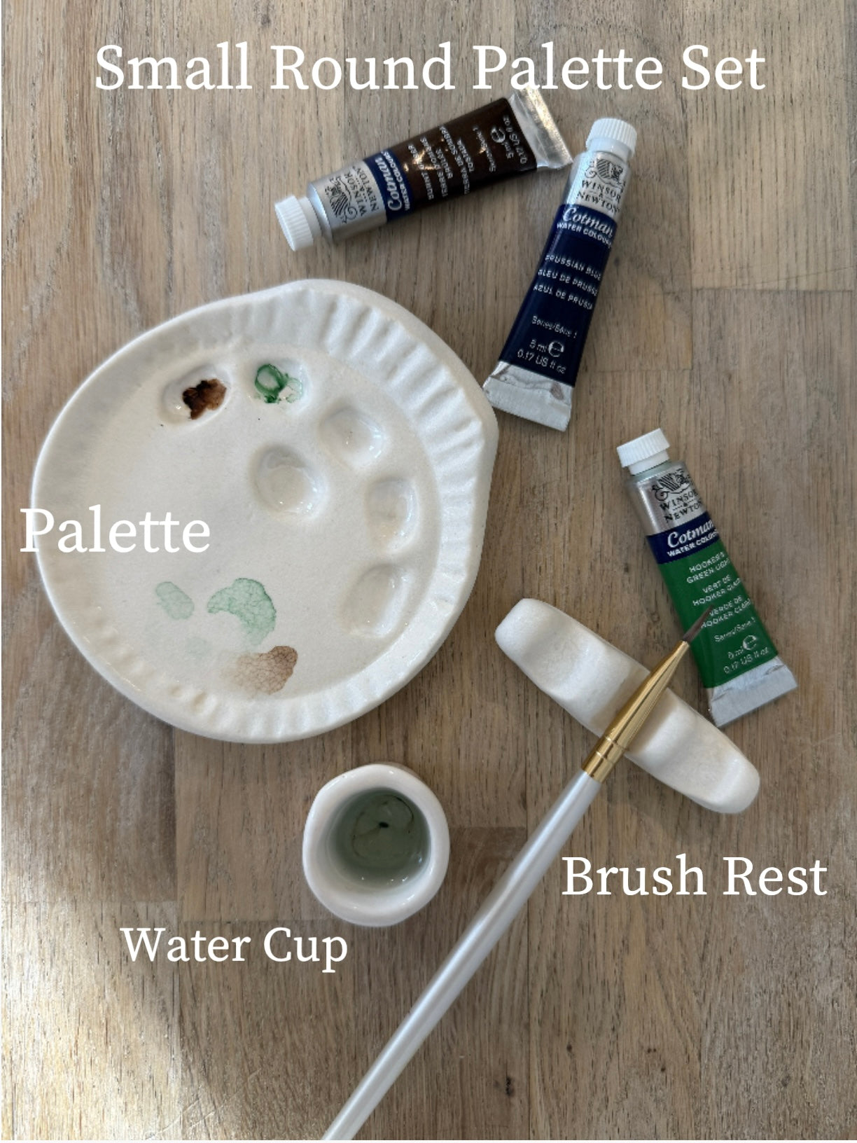 Handmade ceramic watercolor paint palette with mixing wells, a small water cup, and a brush holder.