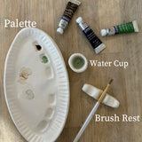 Handmade ceramic watercolor paint palette with mixing wells, a small water cup, and a brush holder.