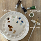 Handmade ceramic watercolor paint palette with mixing wells, a small water cup, and a brush holder.