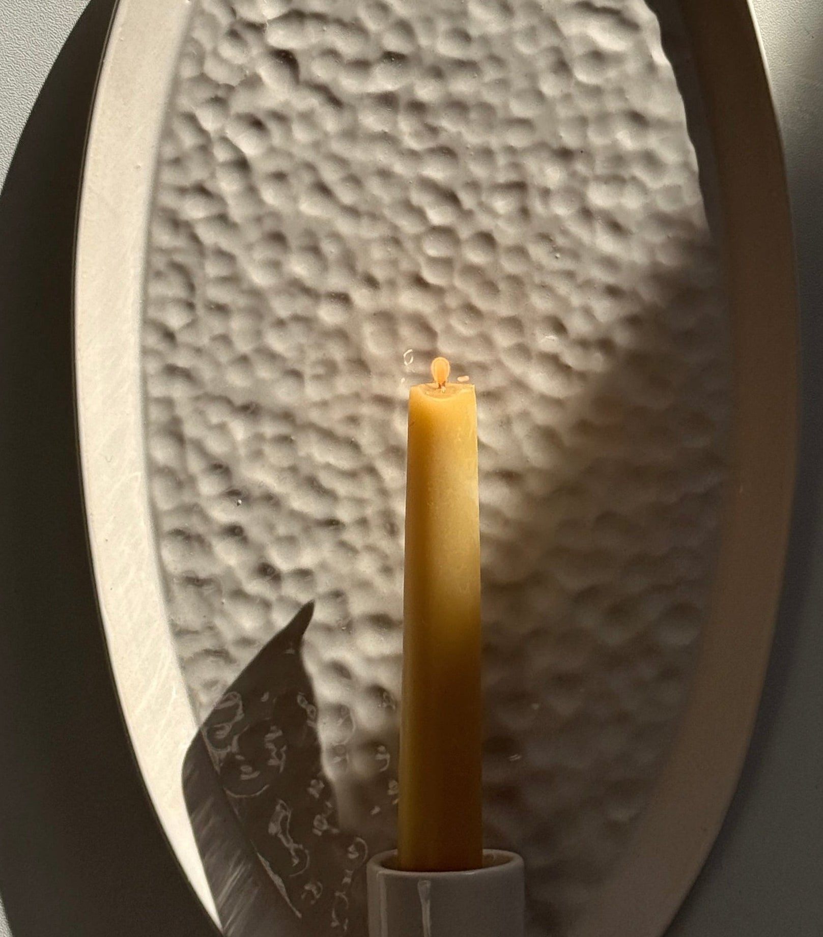 Oval ceramic wall sconce with a softly raised edge and rope hanger