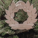 Personalized porcelain laurel wreath ornament with a gloss-white glaze and custom name on linen twine
