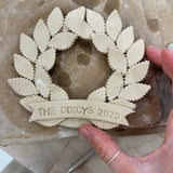 Personalized porcelain laurel wreath ornament with a gloss-white glaze and custom name on linen twine