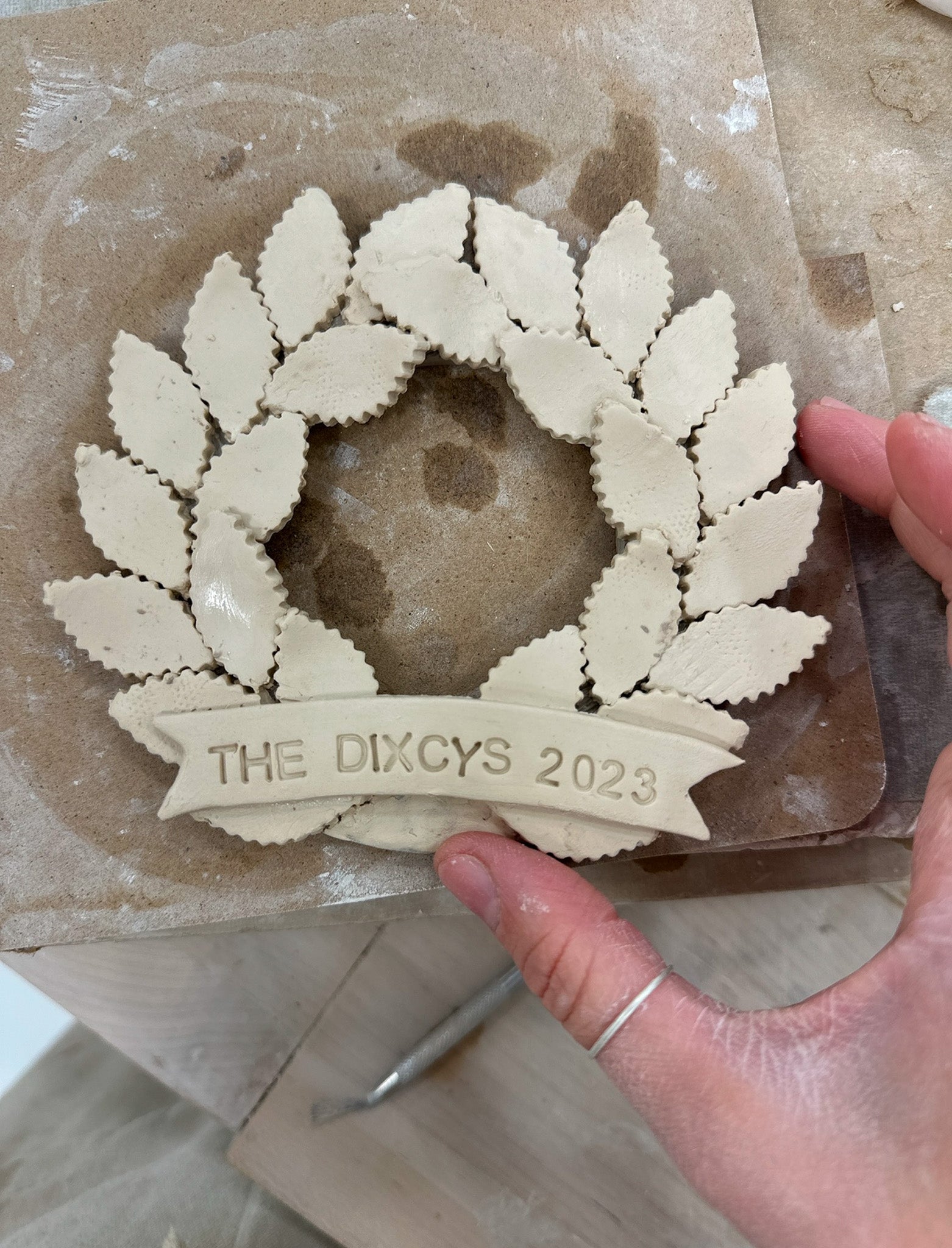 Personalized porcelain laurel wreath ornament with a gloss-white glaze and custom name on linen twine