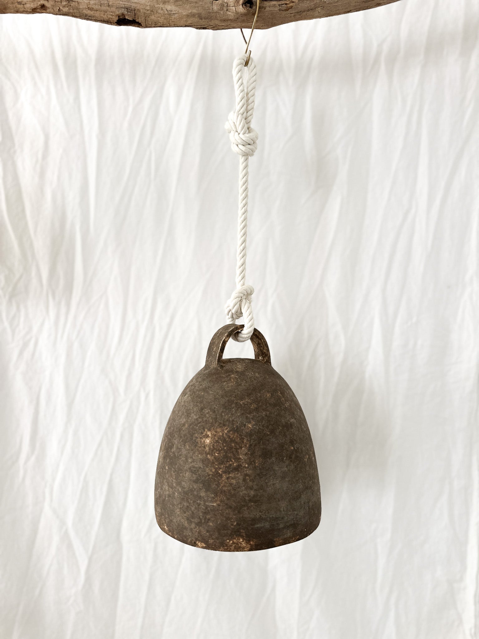 Large neutral-glaze ceramic campana bell styled on a porch