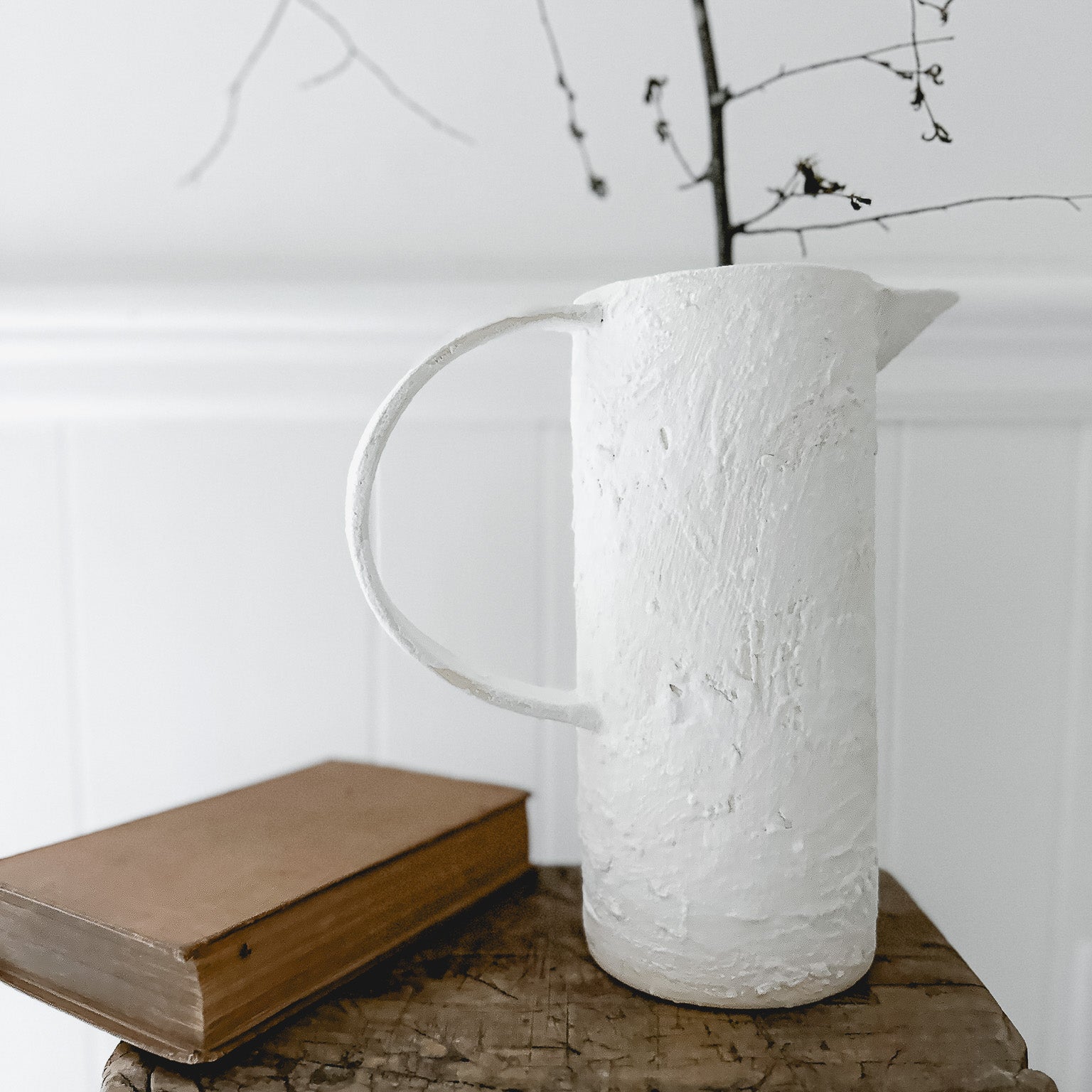 Handmade ceramic pitcher with an oversized handle in a neutral finish