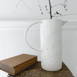 Handmade ceramic pitcher with an oversized handle in a neutral finish
