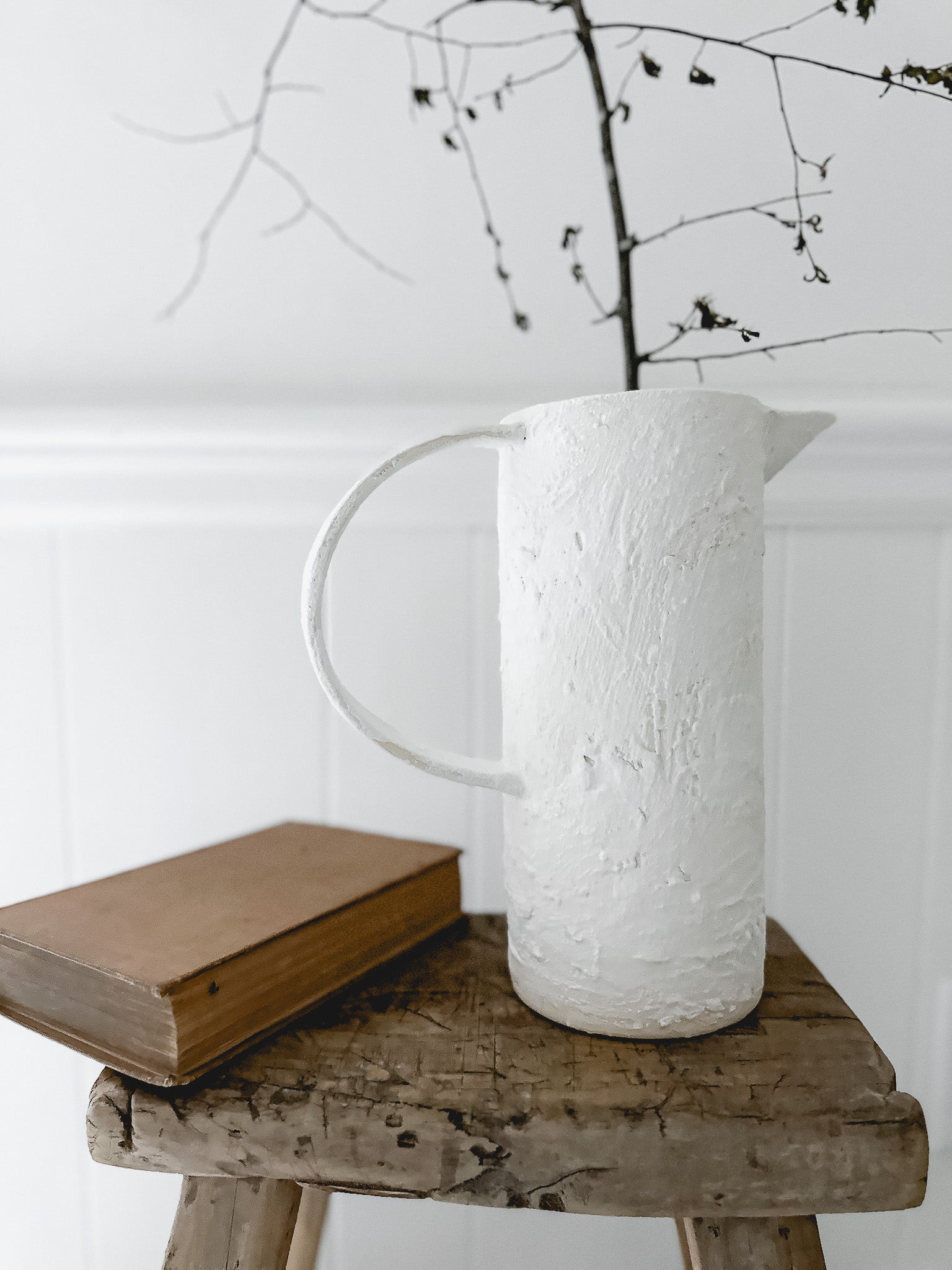 Handmade ceramic pitcher with an oversized handle in a neutral finish