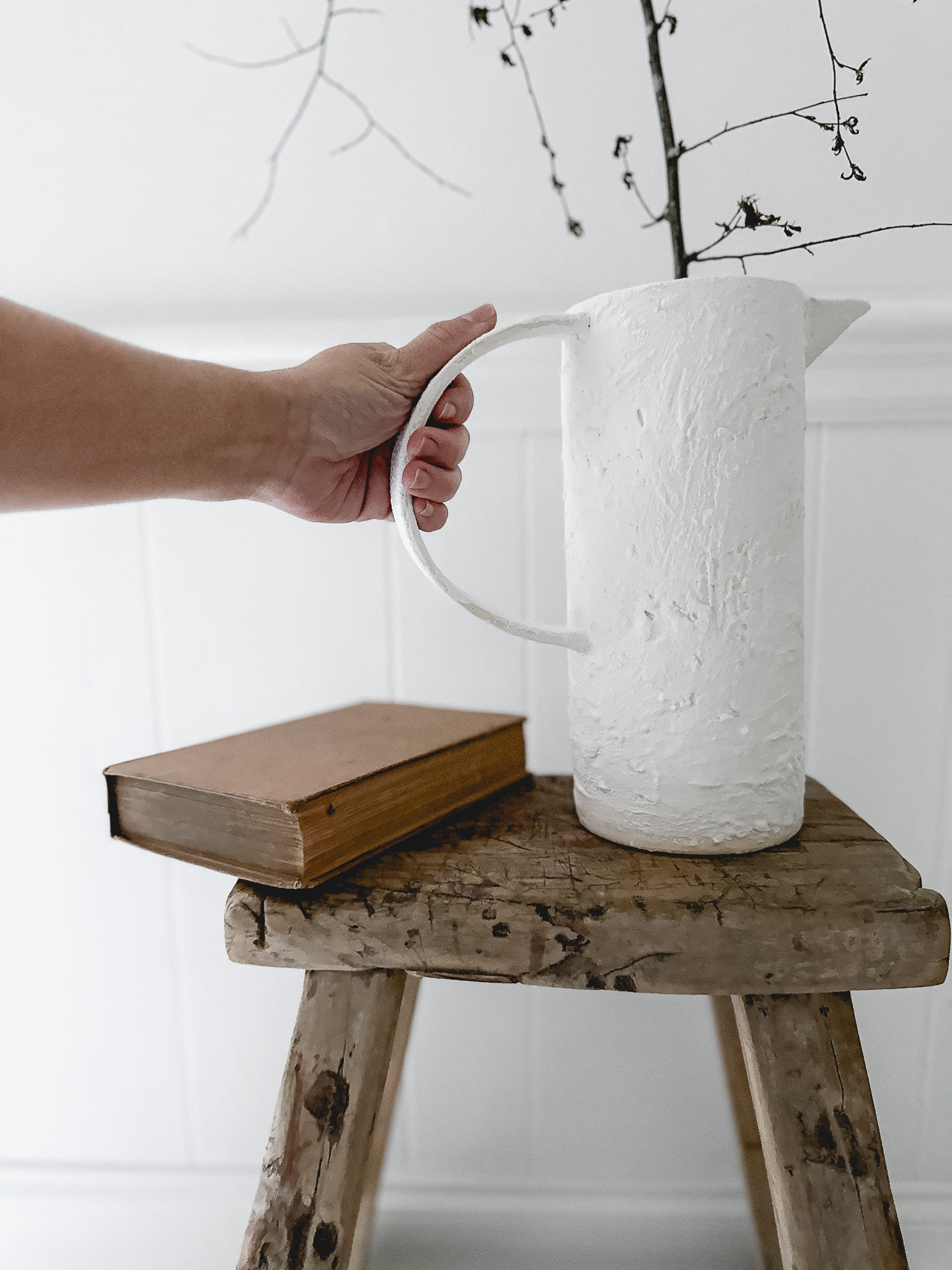 Oversized-handle ceramic pitcher styled with fresh flowers on a counter
