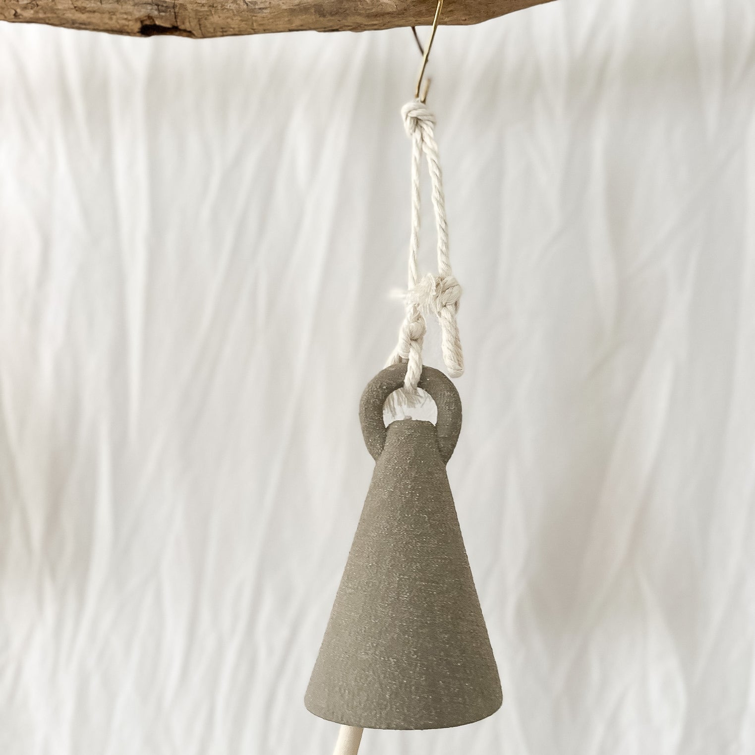 Handmade ceramic spire bell with a tall triangular silhouette in a neutral glaze