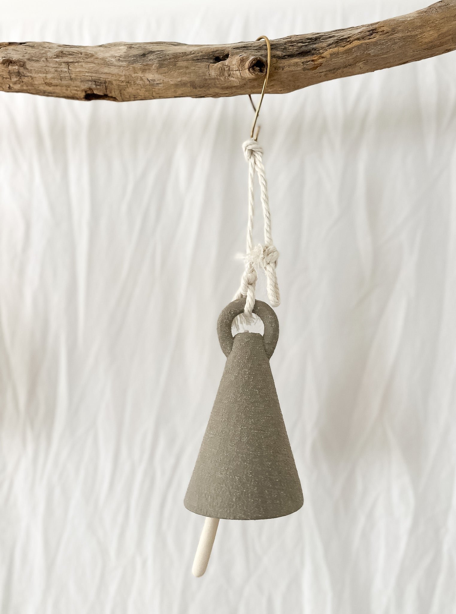 Handmade ceramic spire bell with a tall triangular silhouette in a neutral glaze