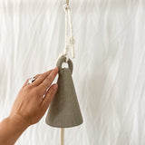 Handmade neutral-glaze ceramic spire bell shown on a porch
