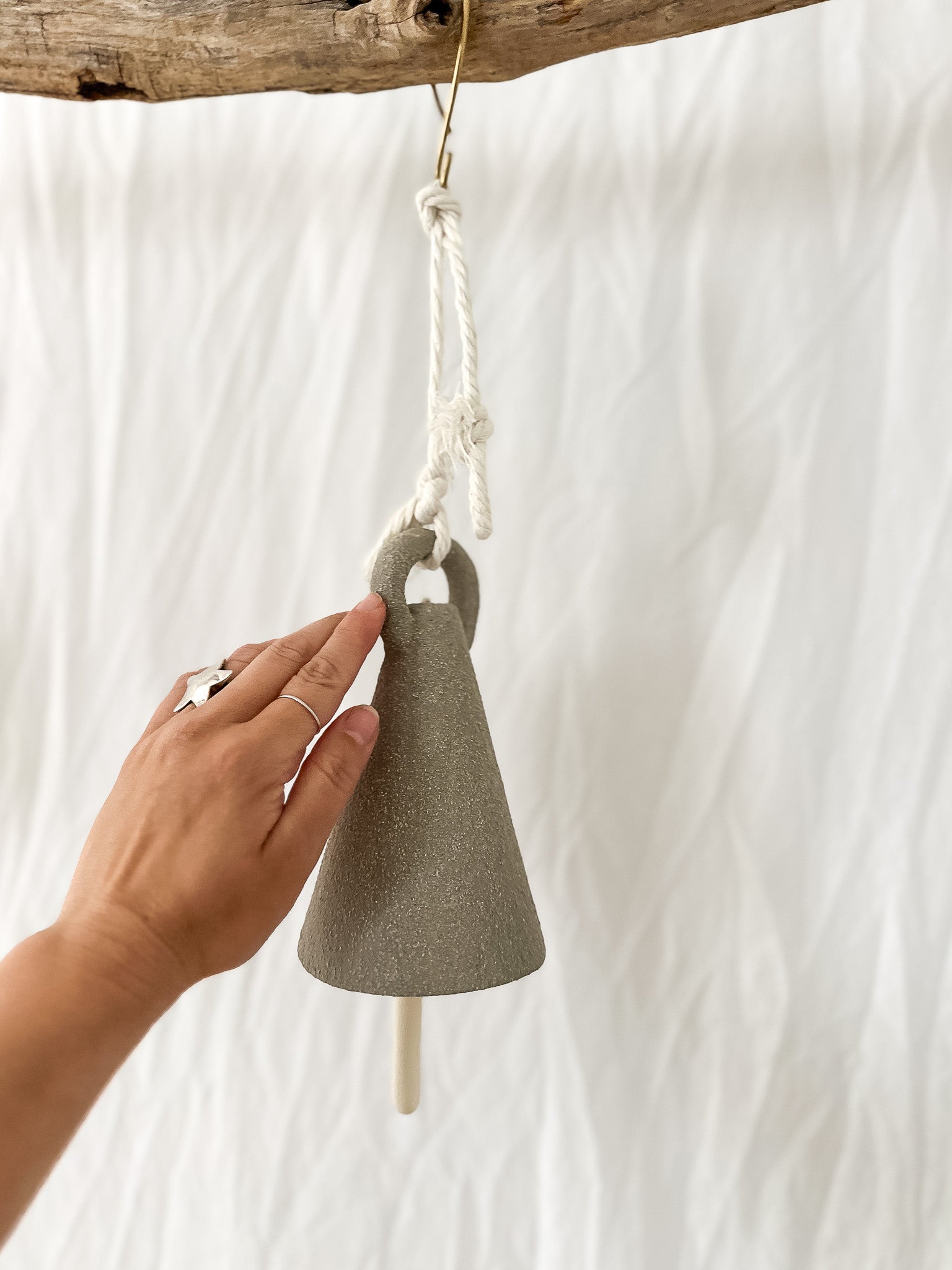 Handmade neutral-glaze ceramic spire bell shown on a porch