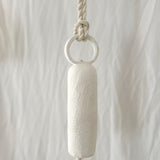Long round-handle ceramic bell hanging on a wall