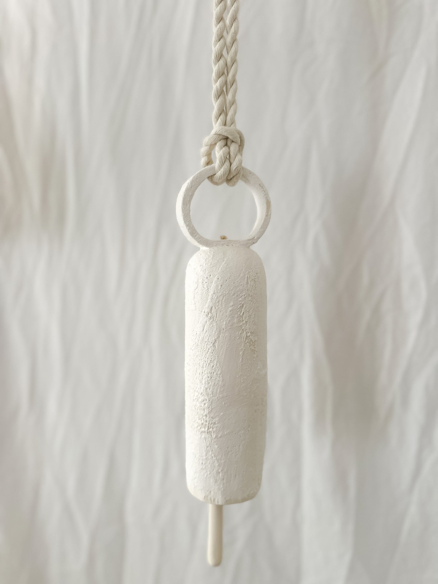 Long round-handle ceramic bell hanging on a wall