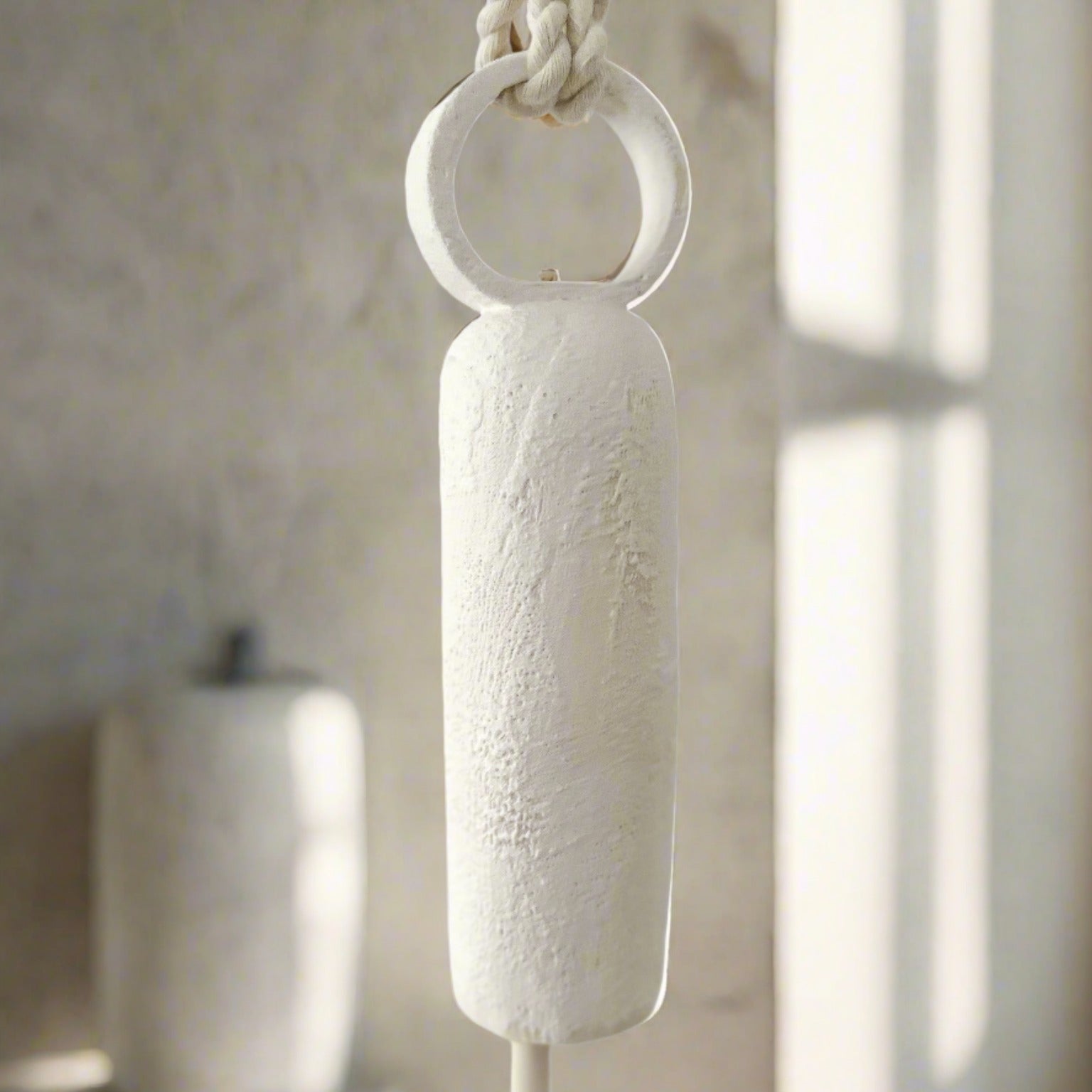 Handmade ceramic wall bell with a long round handle in a neutral glaze