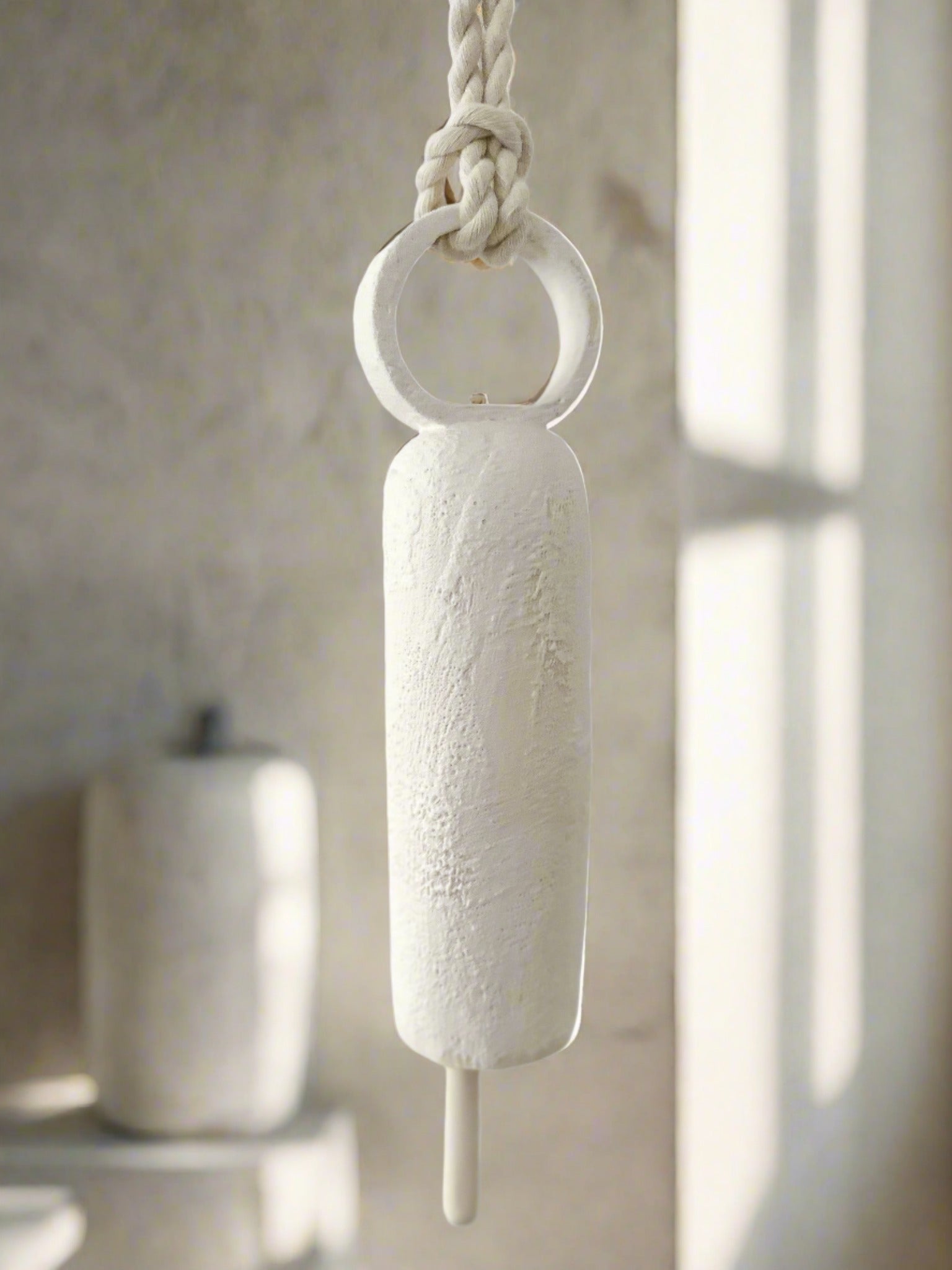 Handmade ceramic wall bell with a long round handle in a neutral glaze
