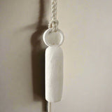 Handmade neutral-glaze ceramic bell with a long handle, detail view