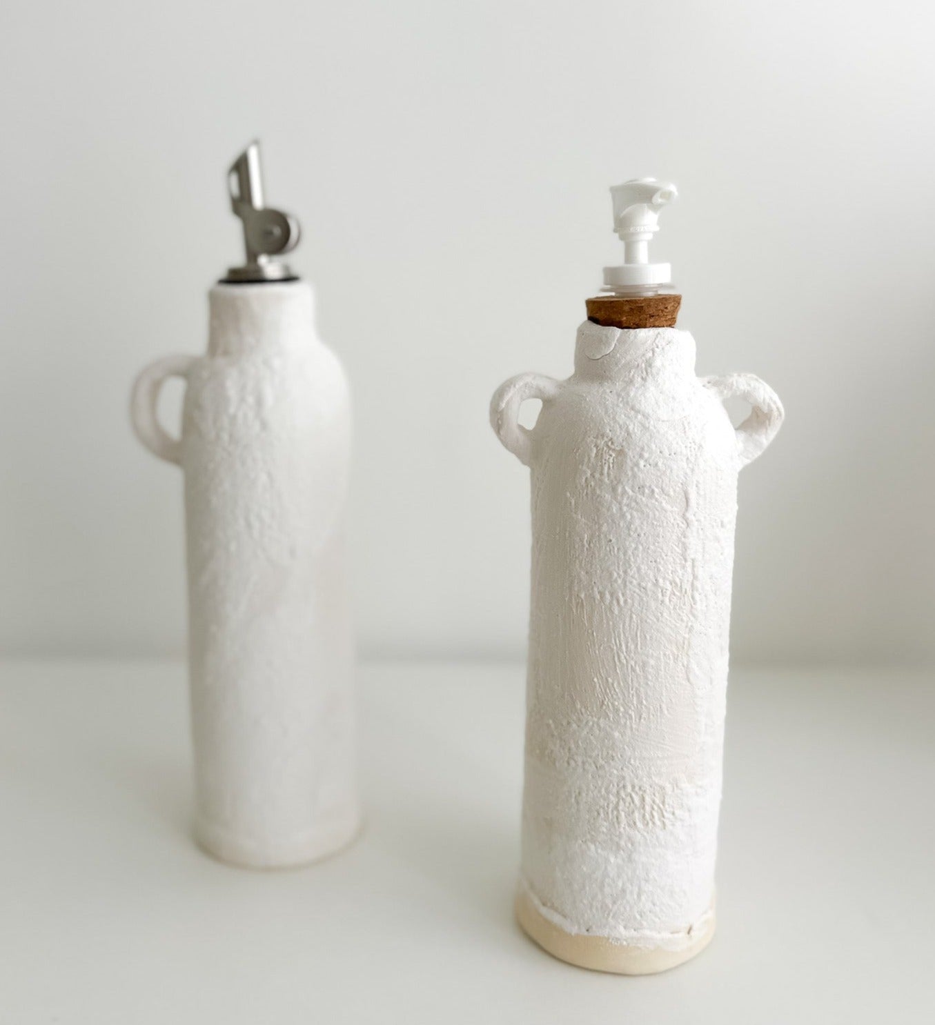 Handmade ceramic oil and soap dispenser bottles grouped together