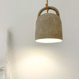 A beige barrel-shaped pendant light hanging from a cord, with light shining from the top.