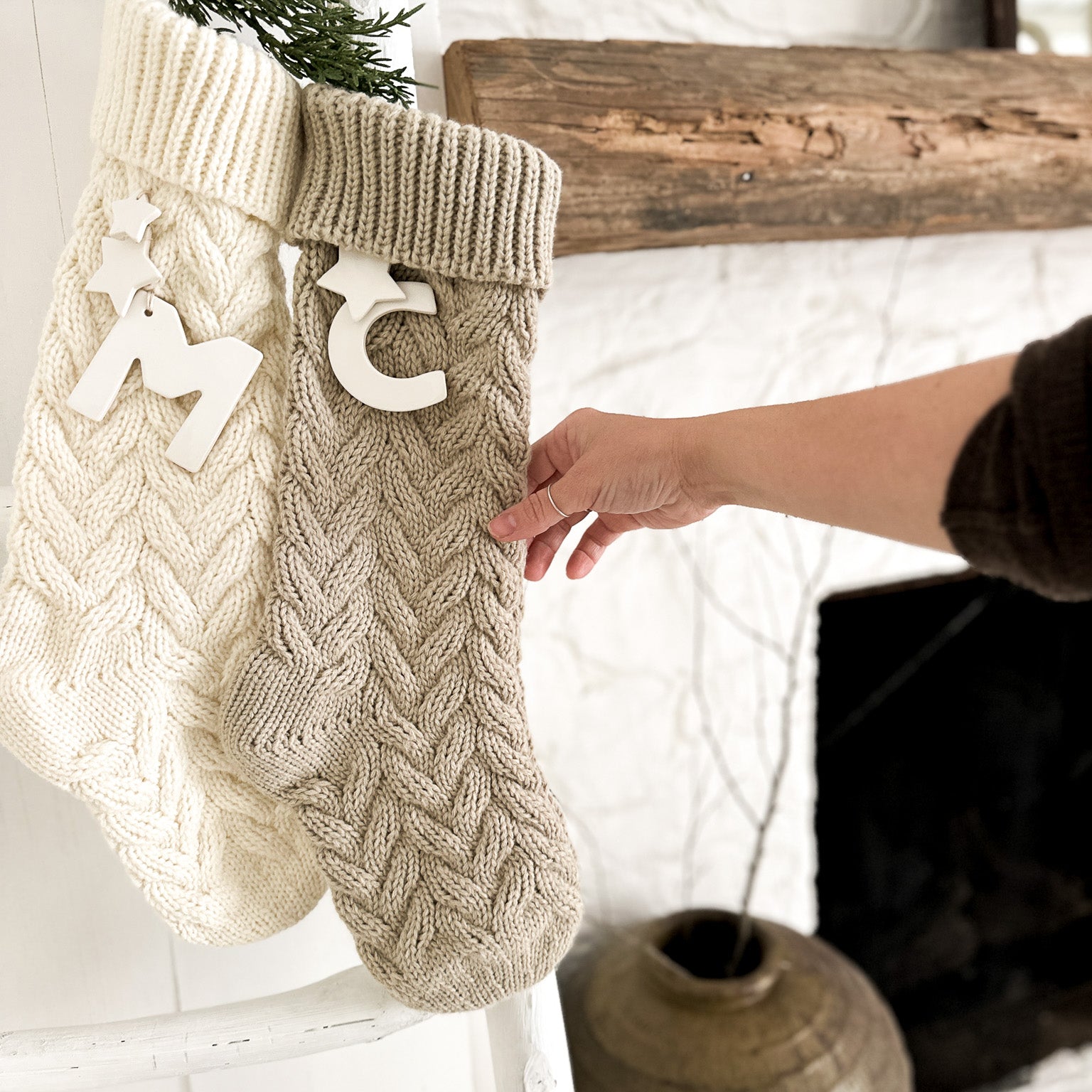 Knitted Christmas stocking with ceramic personalization hung on a mantel