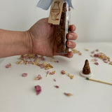 Hand-rolled incense cone burning with a curl of scented smoke