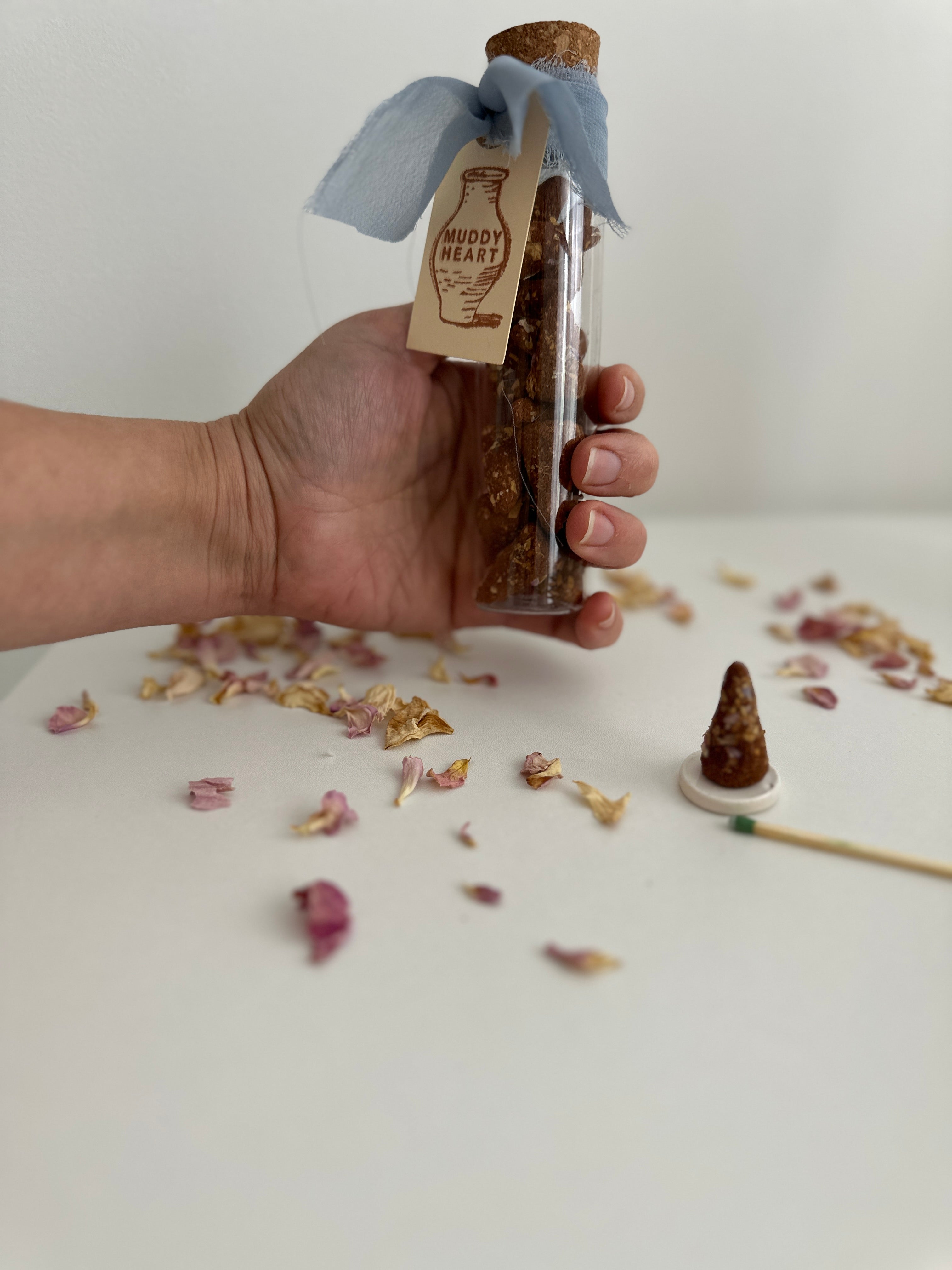 Hand-rolled incense cone burning with a curl of scented smoke