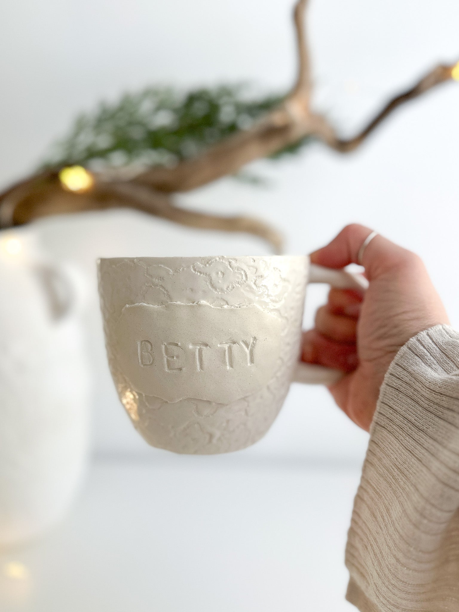 Handmade personalized deep ceramic mug with a glossy white floral-lace textured plaque