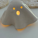 Handmade ceramic ghost luminary glowing softly with an LED tealight candle.