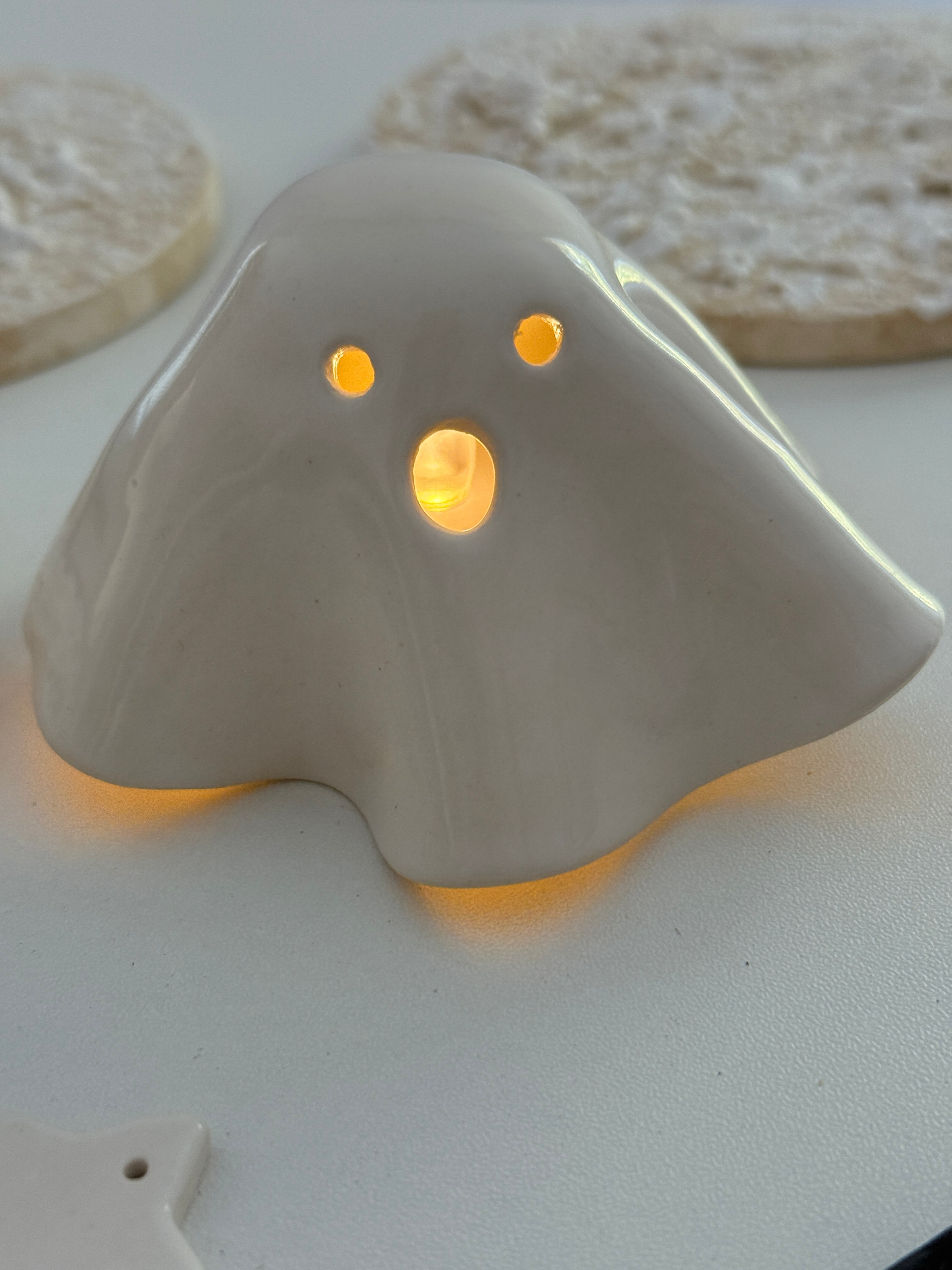 Handmade ceramic ghost luminary glowing softly with an LED tealight candle.