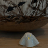 Handmade ceramic ghost luminary glowing softly with an LED tealight candle.