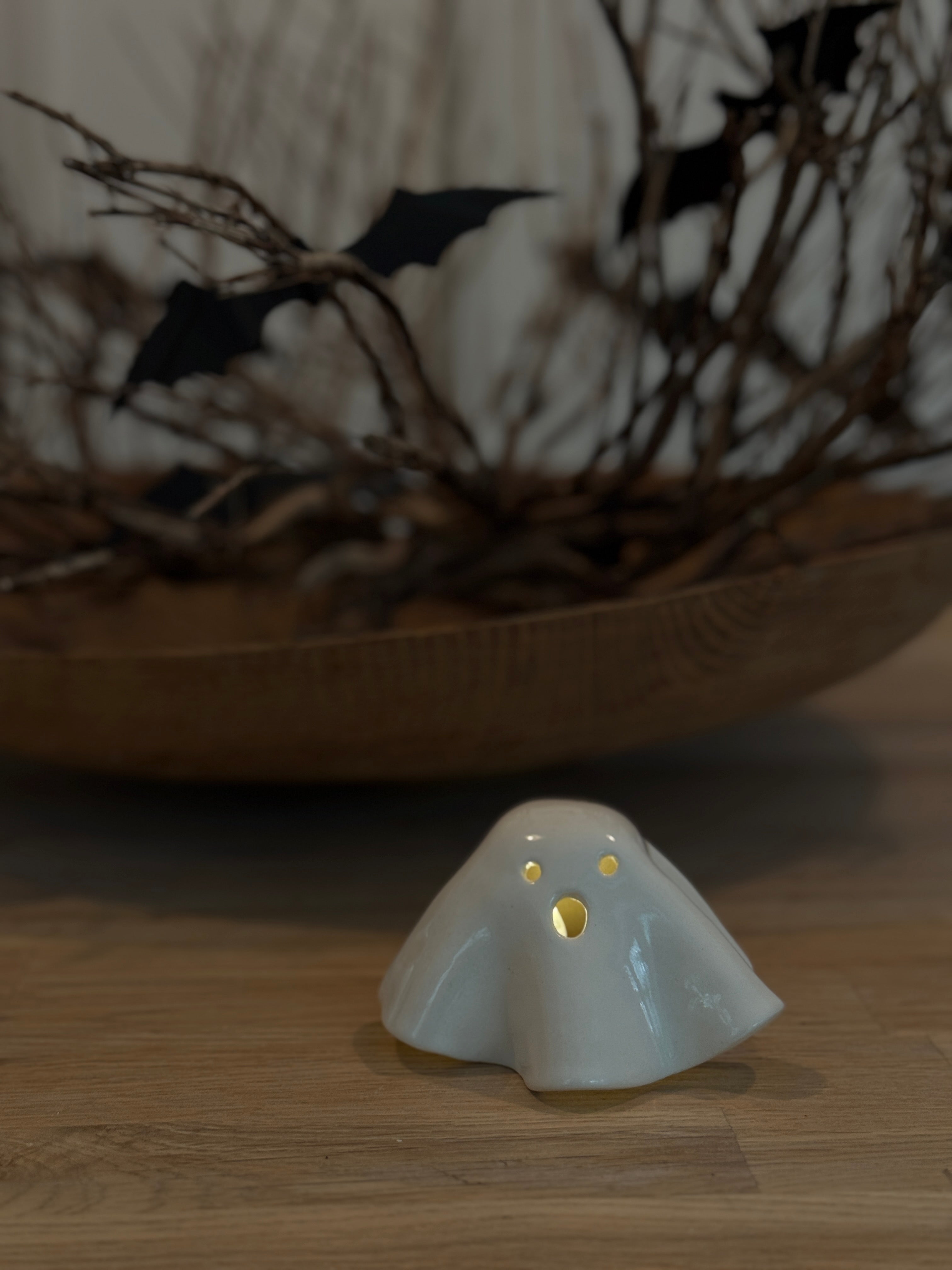 Handmade ceramic ghost luminary glowing softly with an LED tealight candle.
