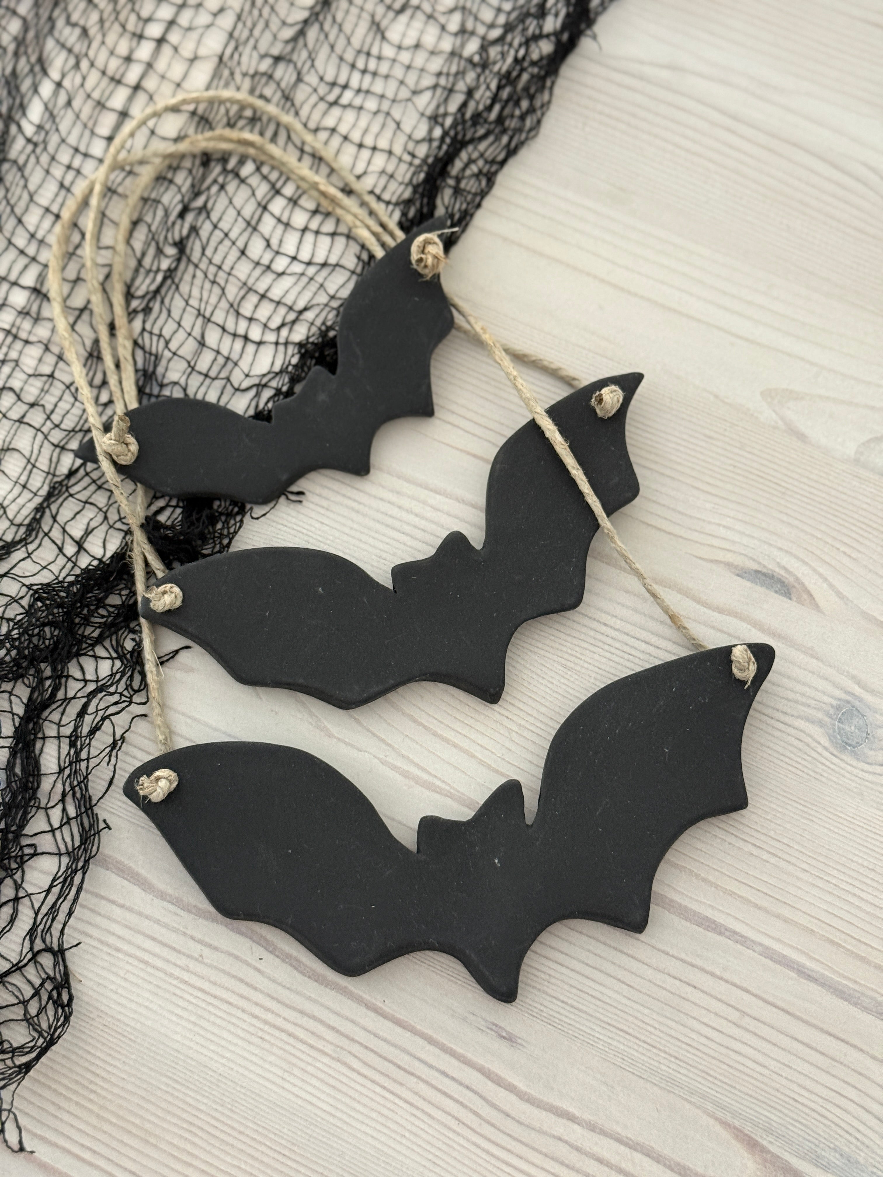 Handmade stoneware bat ornaments in three sizes for hanging on knobs, branches, or wreaths.