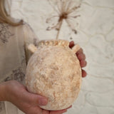 Handmade wild clay ceramic handled jar with a textured natural surface and glazed interior.