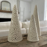 Handmade stoneware tree luminary with star cutouts glowing from an LED tea light