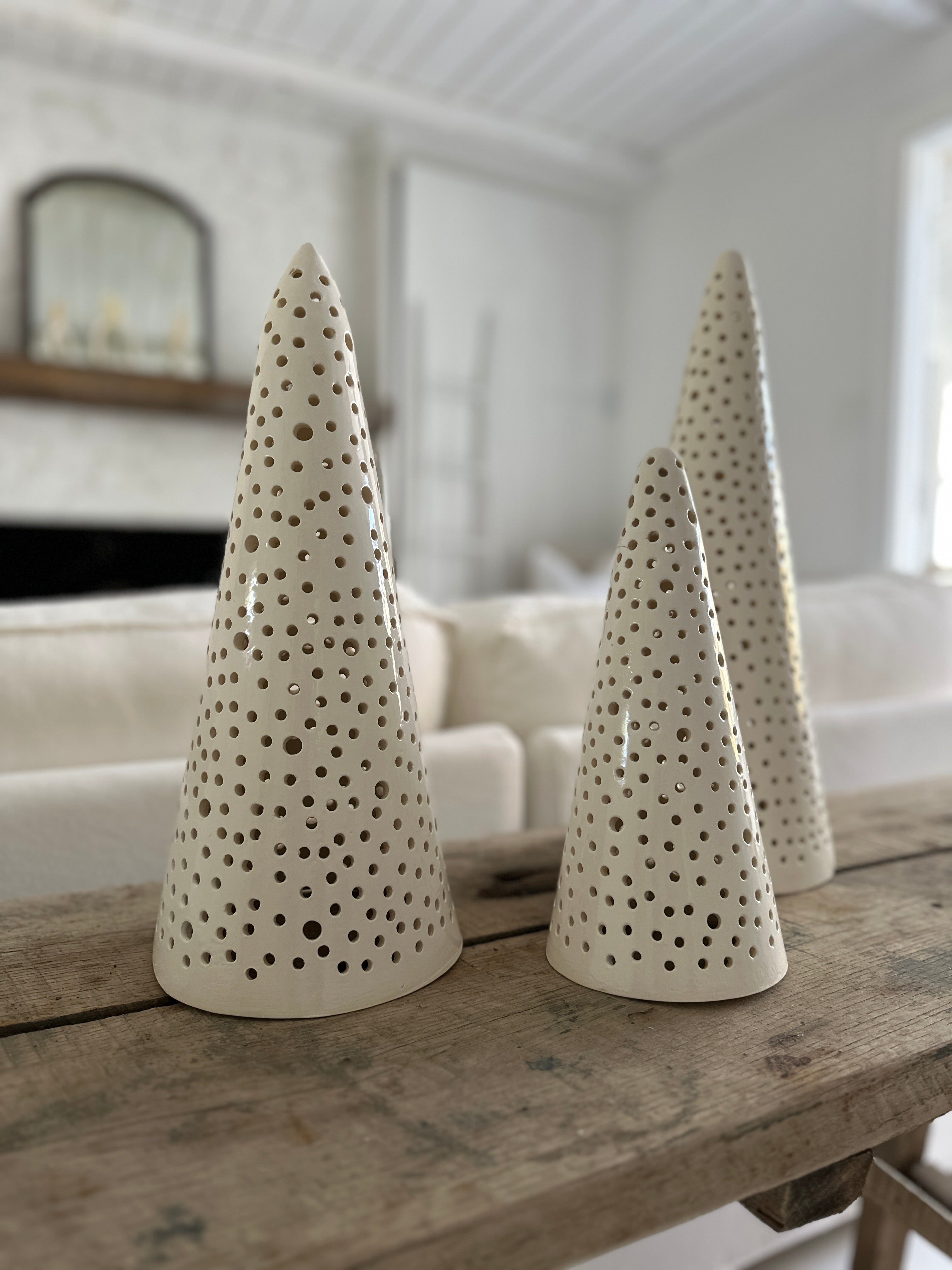 Handmade stoneware tree luminary with star cutouts glowing from an LED tea light