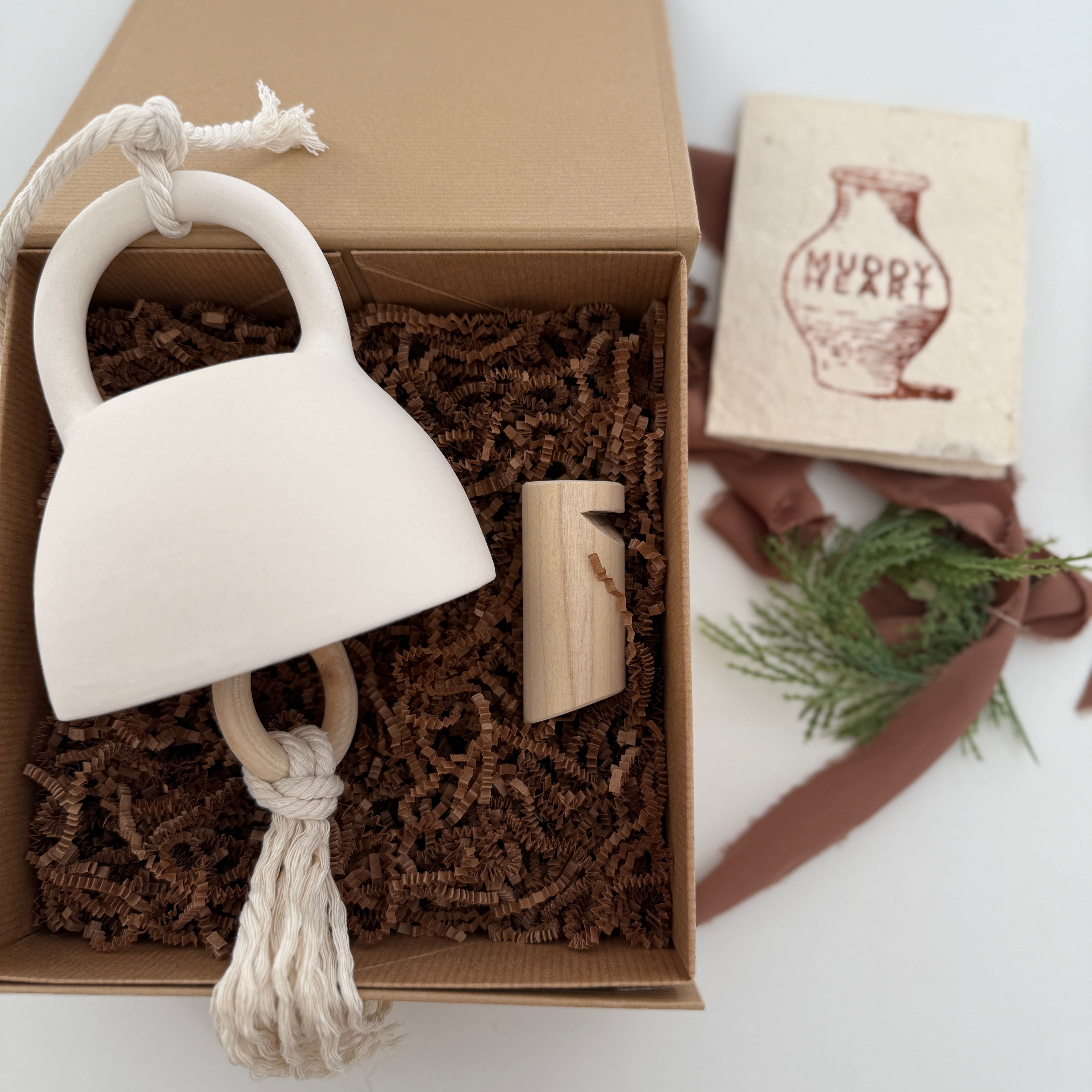 Handmade ceramic bell paired with a solid wood wall peg, styled as a gift set.