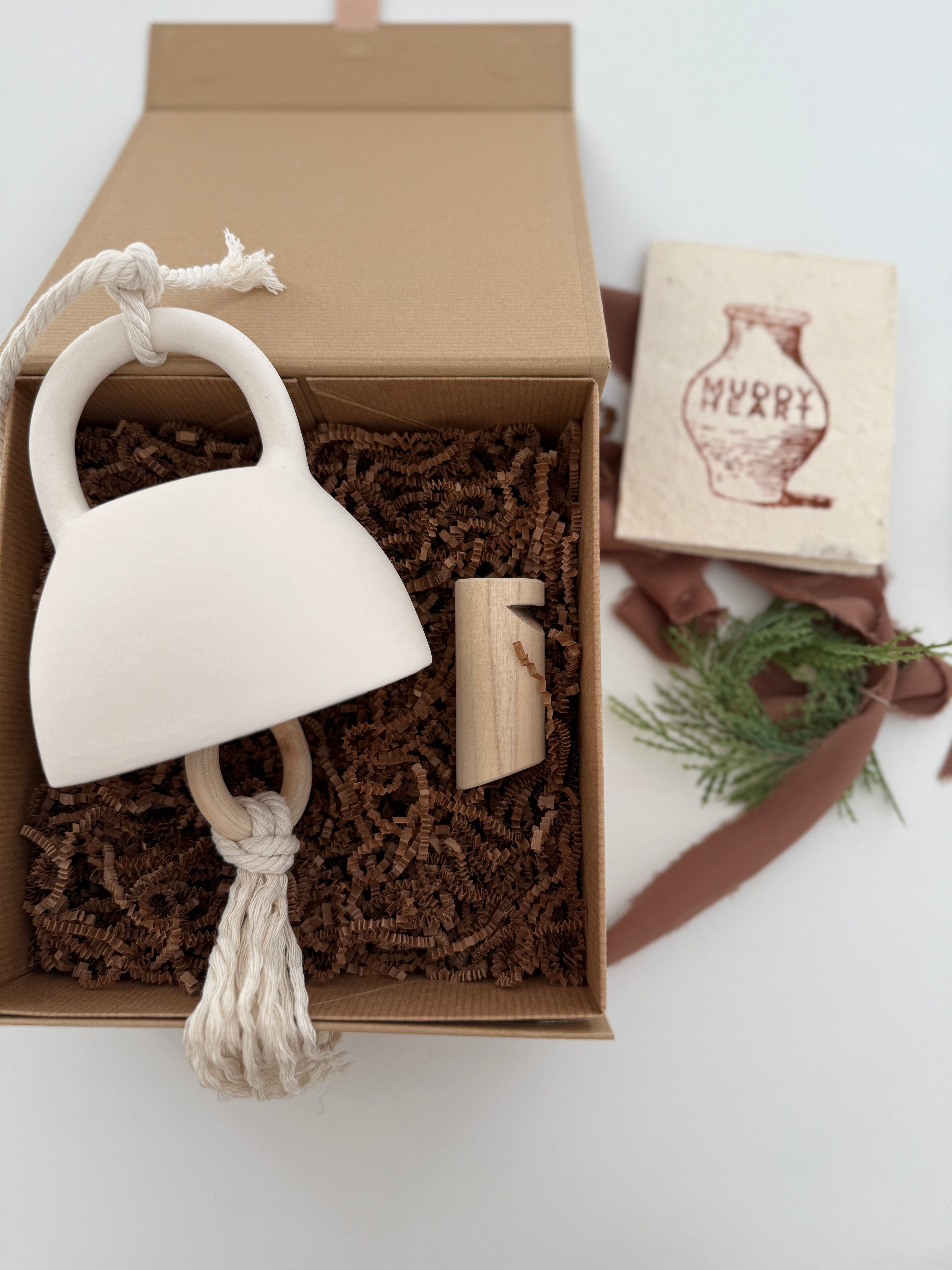 Handmade ceramic bell paired with a solid wood wall peg, styled as a gift set.