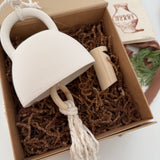 Handmade ceramic bell paired with a solid wood wall peg, styled as a gift set.