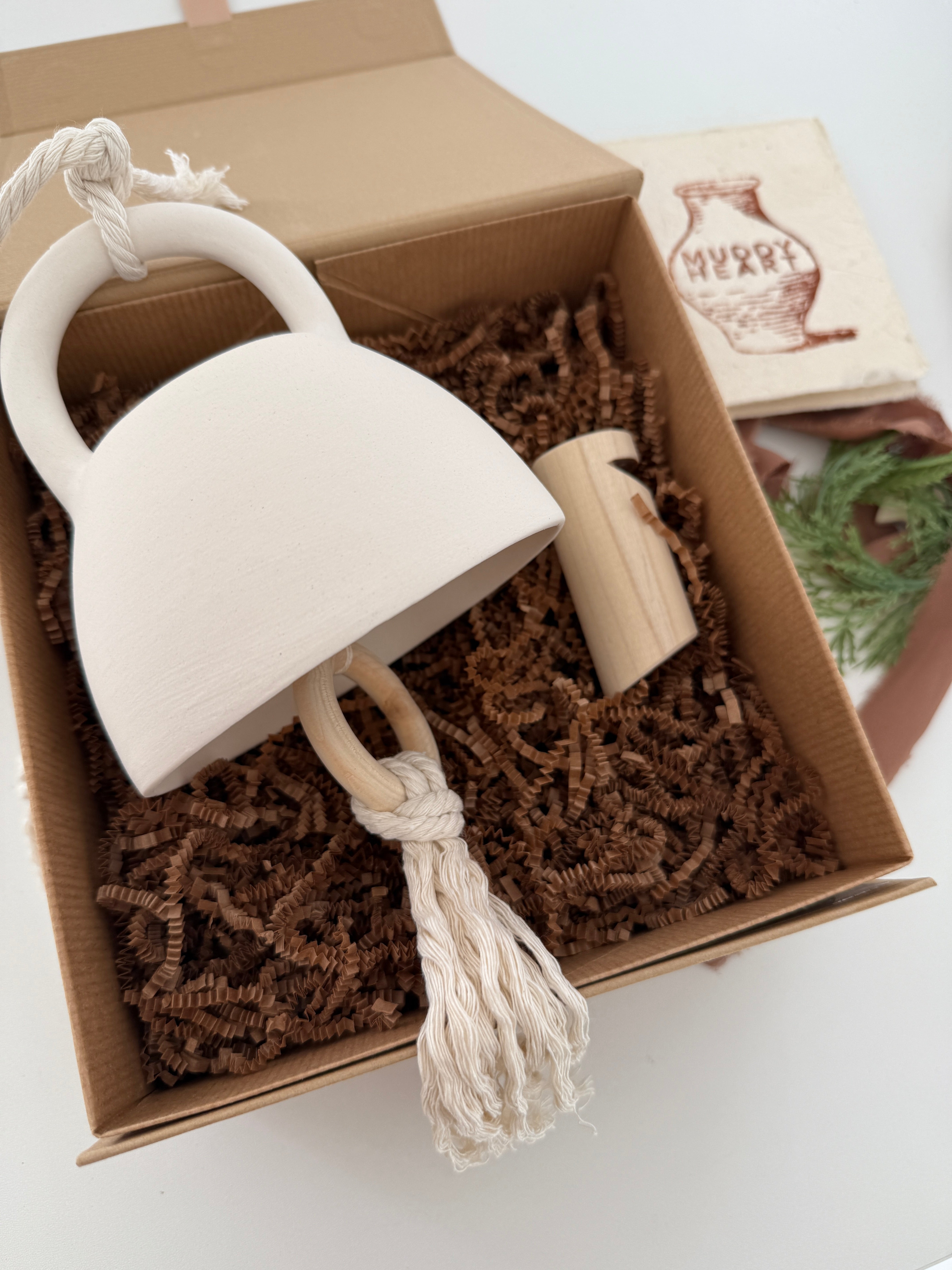 Handmade ceramic bell paired with a solid wood wall peg, styled as a gift set.