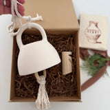 Handmade ceramic bell paired with a solid wood wall peg, styled as a gift set.