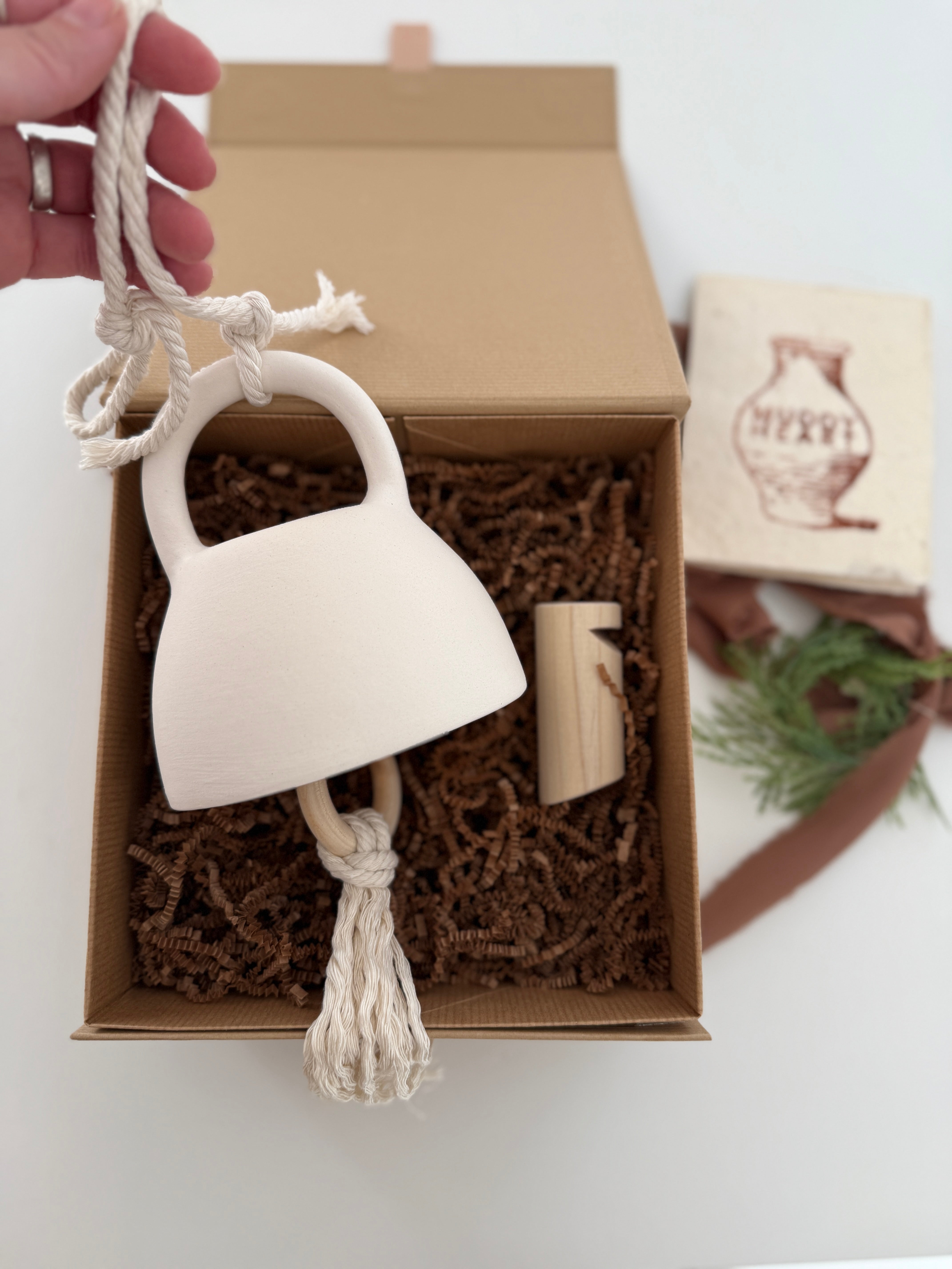 Handmade ceramic bell paired with a solid wood wall peg, styled as a gift set.
