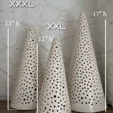 Handmade stoneware tree luminary with star cutouts glowing from an LED tea light