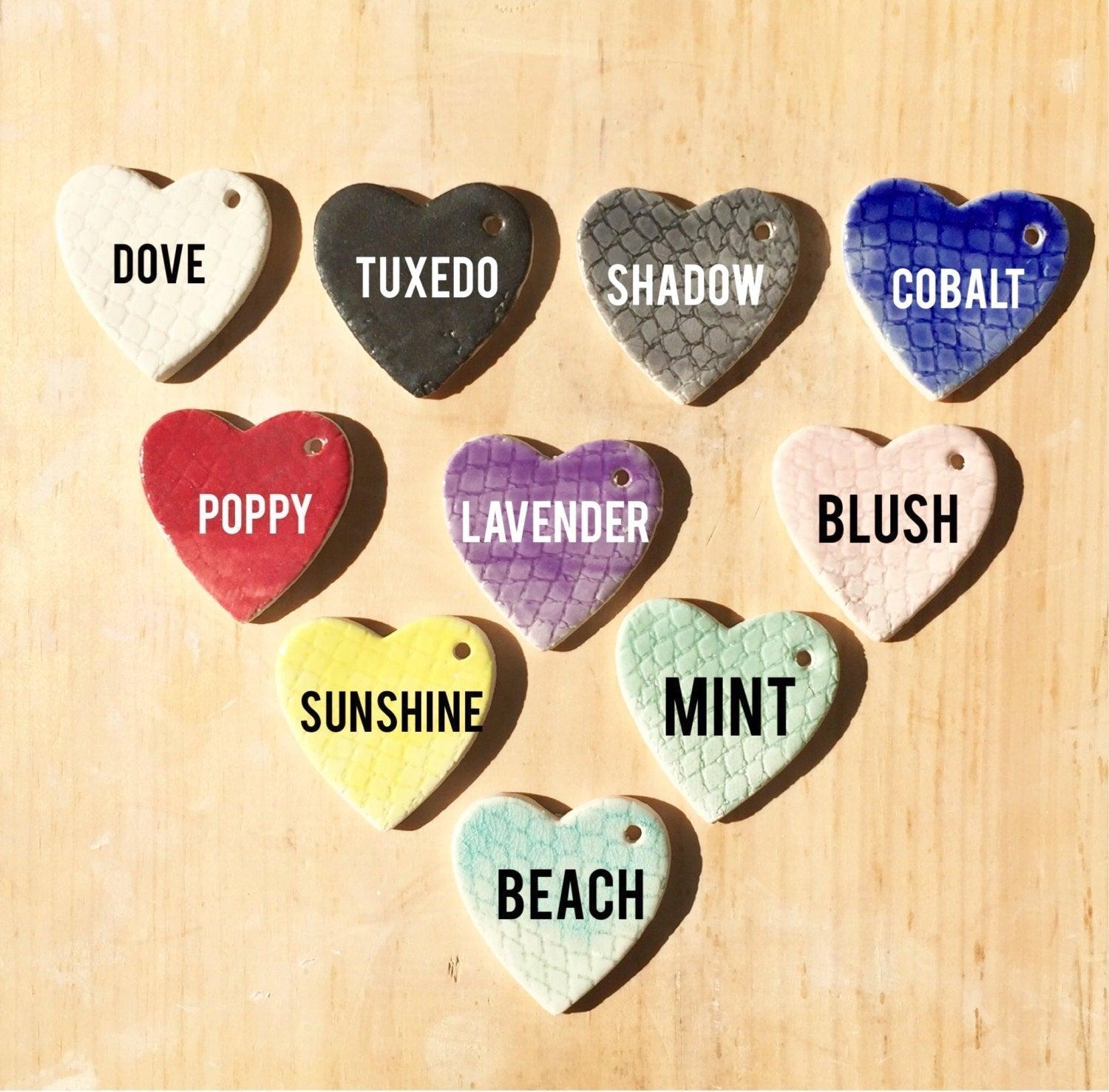 Muddy Heart color chart of glazed ceramic heart tiles labeled Dove, Tuxedo, Shadow, Cobalt, Poppy, Lavender, Blush, Sunshine, Mint and Beach.