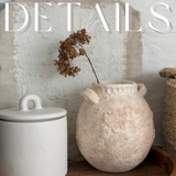 Textured wild clay handmade ceramic handled jar styled on a wooden tray with dried stems.