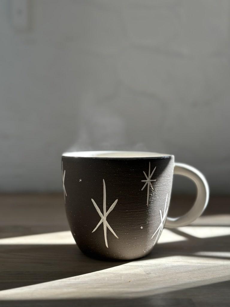 Handmade deep ceramic coffee mug with a carved star and stripe design