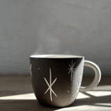 Handmade deep ceramic coffee mug with a carved star and stripe design
